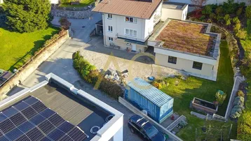 Luftaufnahme des Wohnhauses mit Gründach und einem benachbarten Gebäude mit Photovoltaikanlage.