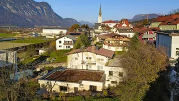 Panoramablick auf das Anwesen, das Dorf und die beeindruckende Berglandschaft im Hintergrund.