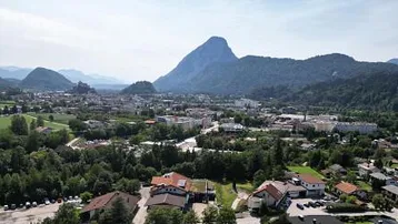 Luftaufnahme einer Stadt in einer malerischen Berglandschaft unter blauem Himmel.