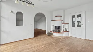 Geräumiges Wohnzimmer mit Holzboden, Kamin und traditionellen Details.