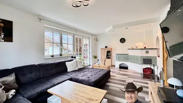 Helles Wohnzimmer mit großem Sofa, Kachelofen und Blick nach draußen.