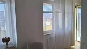 Heller Essbereich mit Holzboden, großen Fenstern und weißer Einrichtung, bietet einen weiten Blick auf die Stadt.