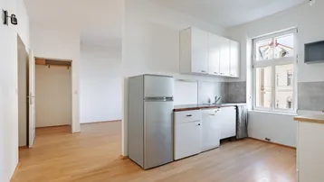 Helle Küche mit Parkettboden, weißen Schränken und Blick auf die Straße.