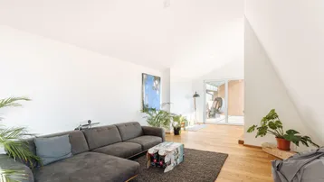 Helles Wohnzimmer mit großem Ecksofa, Holzboden und direktem Zugang zur Terrasse.