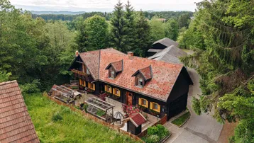 Traditionelles Haus mit rotem Ziegeldach, umgeben von viel Grün und einem gepflegten Gartenbereich.
