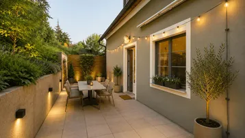 Gemütliche Außenterrasse mit Esstisch, Sitzgelegenheiten und stimmungsvoller Beleuchtung am Abend.