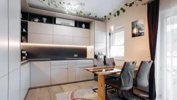 Moderne Küche mit hellen Schränken, Holzboden und integriertem Essbereich, dekoriert mit Pflanzen.