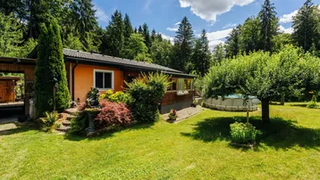 Haus mit großem Garten, umgeben von Bäumen, inklusive Aufstellpool und gepflegter Grünfläche.