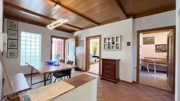 Geräumiger Essbereich mit Holzbalkendecke, Terrakottafliesen und Zugang zu weiteren Räumen.