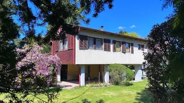 Freistehendes Haus mit großem Garten und blühenden Bäumen, umgeben von viel Grün.