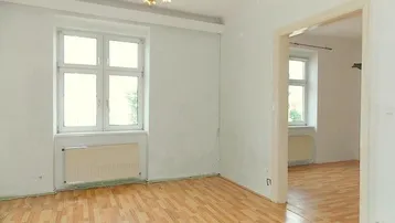 Helles Zimmer mit Laminatboden und zwei großen Fenstern, bereit zur individuellen Gestaltung.