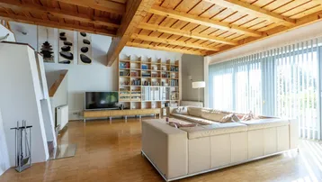 Großzügiges Wohnzimmer mit Holzbalkendecke, Parkettboden und Kamin.