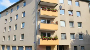 Mehrfamilienhaus mit mehreren Balkonen und Garagen im Erdgeschoss.
