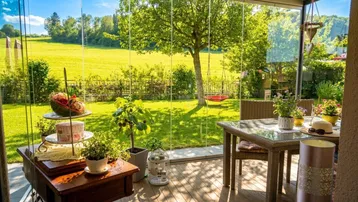 Heller Wintergarten mit Glaswänden, Esstisch und weitem Blick auf den grünen Garten.