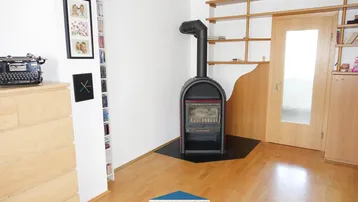 Wohnzimmer mit gemütlichem Holzofen, Holzfußboden und praktischen Einbauregalen.