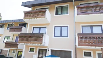 Mehrfamilienhaus mit mehreren Balkonen und Garagenzugang in gepflegtem Zustand.