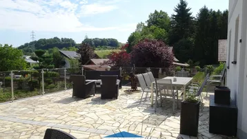 Geräumige Terrasse mit modernen Outdoor-Möbeln und weitem Blick über die grüne Landschaft.