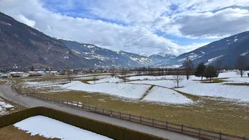 Balkon mit weitem Blick auf die schneebedeckten Berge und die umliegende grüne Landschaft.