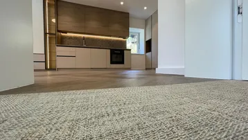 Moderne Küche mit Holz- und beigefarbenen Schränken, integriertem Backofen und Fischgrätparkettboden.