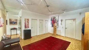Geräumiger Flur mit hellem Holzfußboden, rotem Teppich und mehreren Türen, der zu verschiedenen Räumen führt.