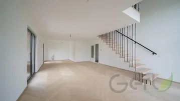 Heller, offener Wohnbereich mit modernem Fischgrätparkett und eleganter Treppe zum Obergeschoss.