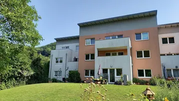 Moderne Wohnanlage mit gepflegtem Rasen, Sitzbereich im Freien und Bergblick.