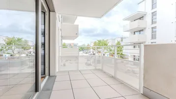 Heller Balkon mit Fliesenboden und moderner Brüstung, bietet einen weiten Blick auf die Umgebung.