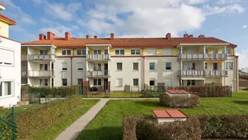 Ansicht eines modernen Wohngebäudes mit mehreren Balkonen und gepflegter Grünfläche im Innenhof.