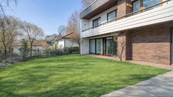 Modernes Haus mit gepflegtem Rasen und Zugang zu großen Fenstern im Erdgeschoss.