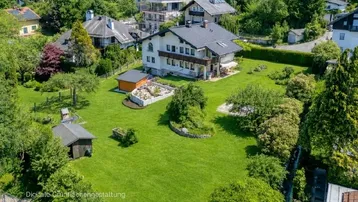 Luftaufnahme eines Hauses mit großem, gepflegten Garten und umliegender grüner Landschaft.