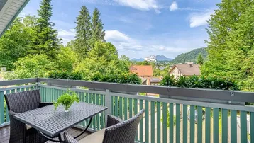 Gemütlicher Balkon mit Sitzgelegenheiten und weitem Blick ins Grüne und auf die Berge.