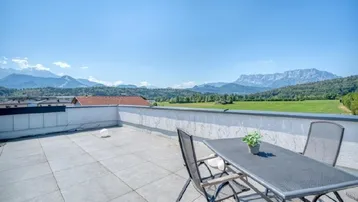 Geräumige Dachterrasse mit Fliesenboden, Sitzgelegenheiten und beeindruckendem Panoramablick auf die Berge.