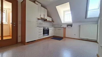 Dachgeschosswohnung mit kleiner Einbauküche, Dachschrägen und hellen Böden.