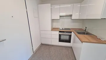 Kompakte, moderne Küche mit weißen Hochglanzfronten und Holzarbeitsplatte.