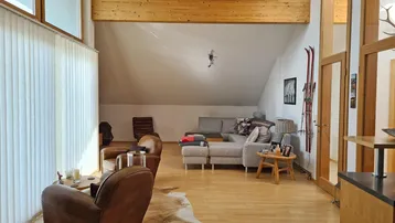 Geräumiges Wohnzimmer mit Holzboden, bequemer Couch und schrägen Wänden im Dachgeschoss.