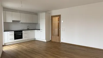 Moderne Einbauküche mit weißen Schränken und dunkler Arbeitsplatte in einem offenen Wohnbereich.