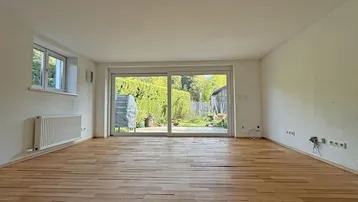 Geräumiges Wohnzimmer mit Holzboden und großer Schiebetür zum Garten.