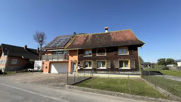 Ansicht des Hauses von der Straße mit Garage, Balkon und Solaranlage auf dem Dach.