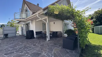 Große gepflasterte Terrasse mit Sitzgelegenheiten und überdachtem Bereich am Haus.