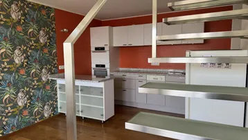 Moderne Küche mit weißen Schränken, Granitarbeitsplatte und auffälliger Tapete, verbunden mit einer Treppe.