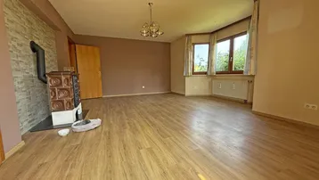 Geräumiges Wohnzimmer mit Laminatboden, Kachelofen und Erkerfenstern.