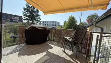 Geräumiger Balkon mit Fliesenboden, Markise und Grillbereich, ideal für entspannte Stunden im Freien.