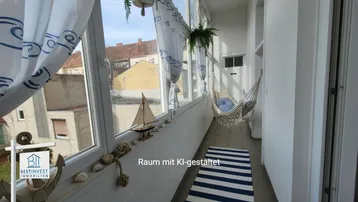 Verglaste Loggia mit maritimer Dekoration, Hängematte und Blick auf die umliegenden Gebäude.