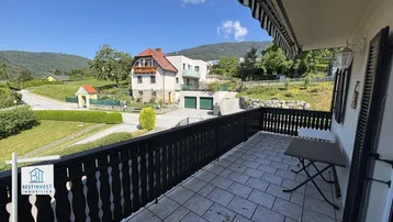 Großer Balkon mit Fliesenboden und weitem Blick auf die umliegende Landschaft und Berge.