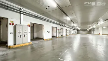 Große, helle Tiefgarage mit Betonboden, vielen Toren und elektrischen Schaltkästen.