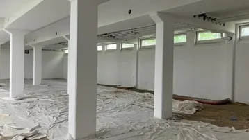 Großer, leerer Raum mit weißen Säulen und Schutzplanen auf dem Boden, bereit für den Ausbau.