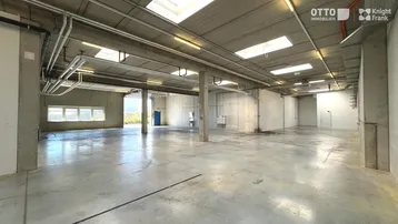 Geräumige Lagerhalle mit hohen Decken, Betonboden und Oberlichtern, ideal für industrielle Nutzung.