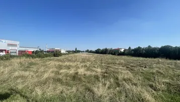 Weitläufiges Grundstück mit Grasfläche und Blick auf umliegende Gebäude unter klarem Himmel.