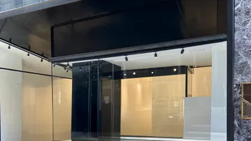 Moderne Ladenfront mit großen Glasfenstern und schwarzem Rahmen, ideal für Einzelhandel oder Büroflächen in der Stadt.