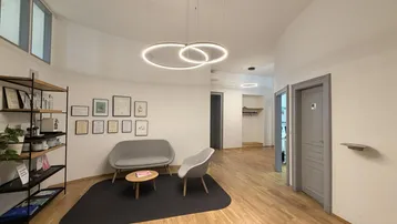 Moderner Empfangsbereich mit bequemen Sitzgelegenheiten, Holzboden und stilvollen Hängeleuchten.